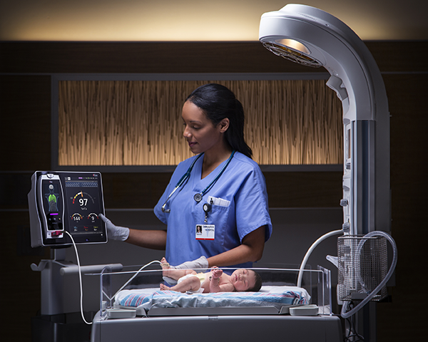 Clinicien qui vérifie le moniteur Root fixé au bébé dans l’unité de soins intensifs néonataux