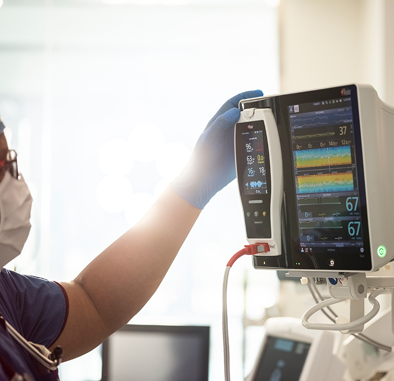 Professionnel de santé interagissant avec un système Masimo de surveillance des patients affichant l’évolution avancée des signes vitaux.